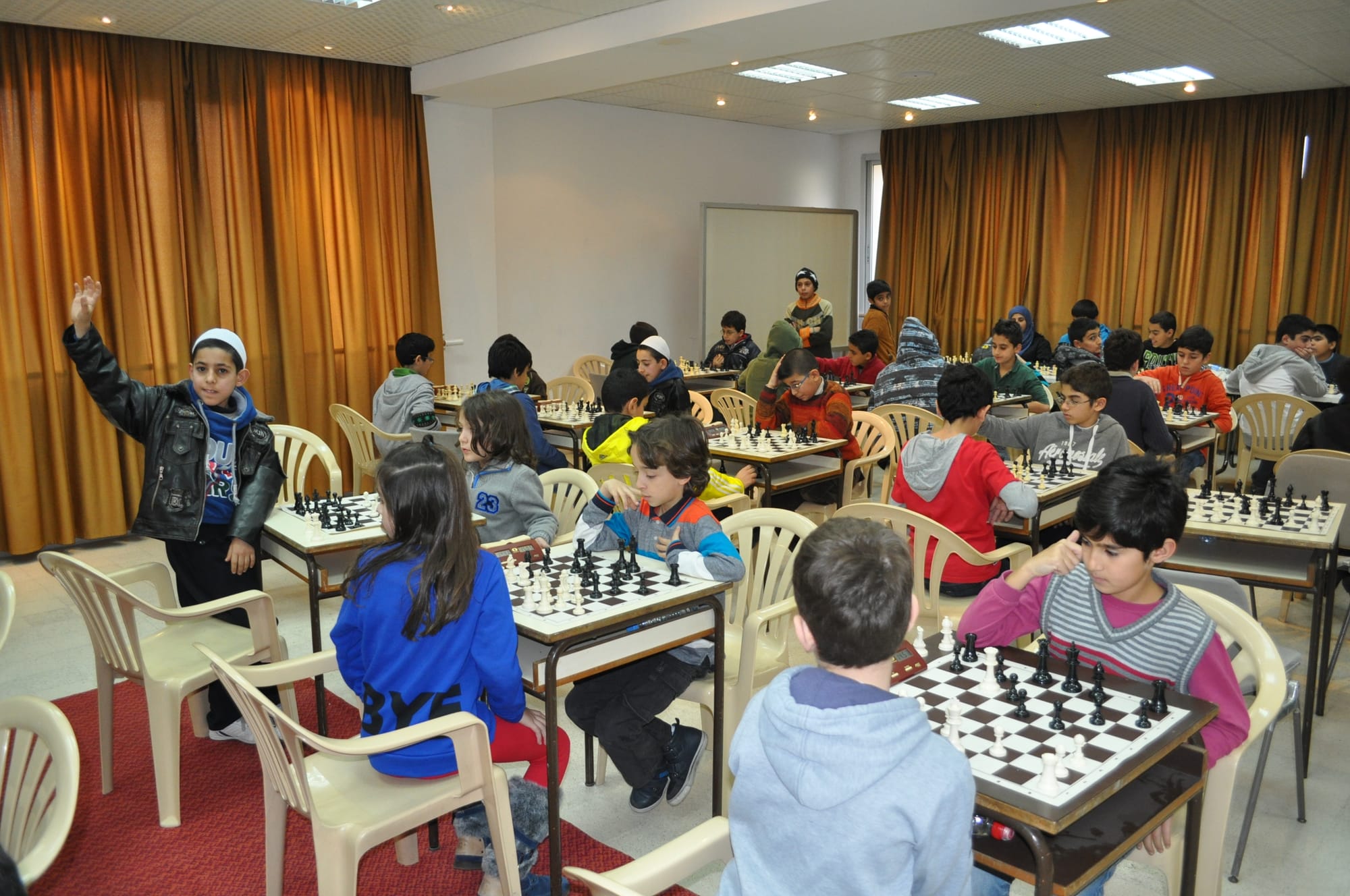 Boys and girls competing across a full junior tournament hall