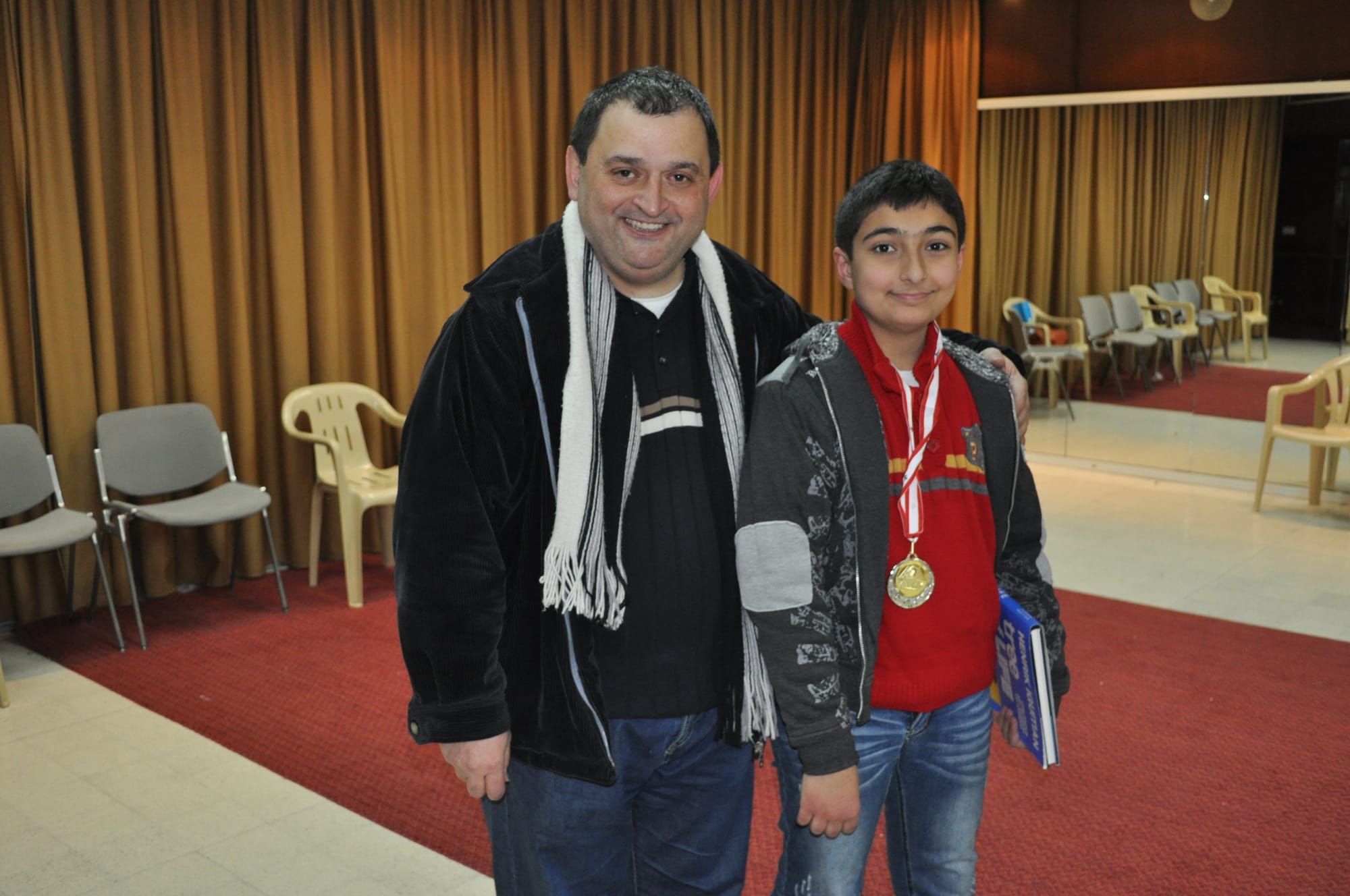 Coach and his student smile after the boy wins his medal