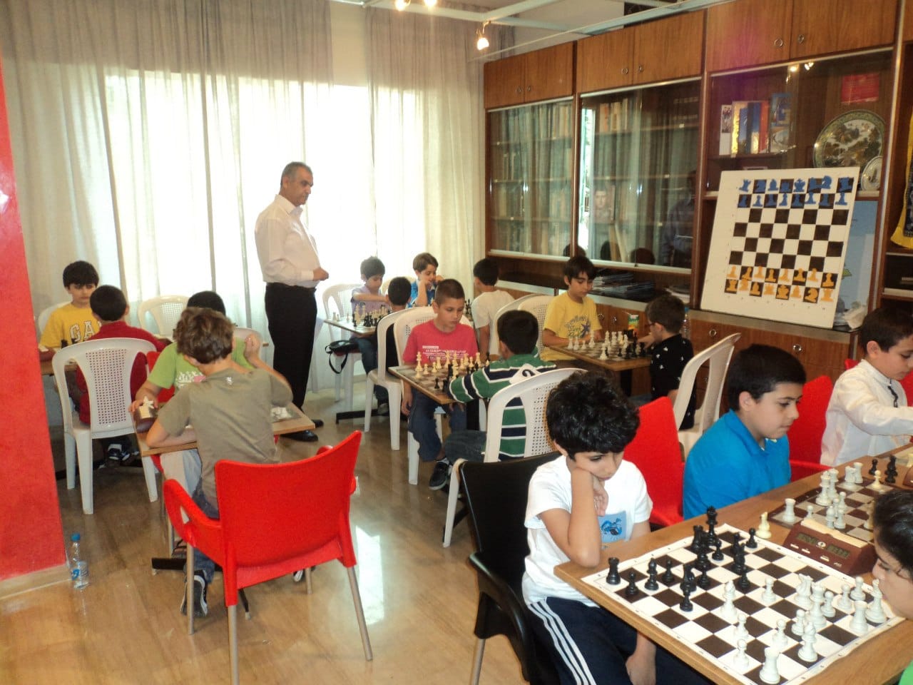 A full room of young players competing under coach supervision